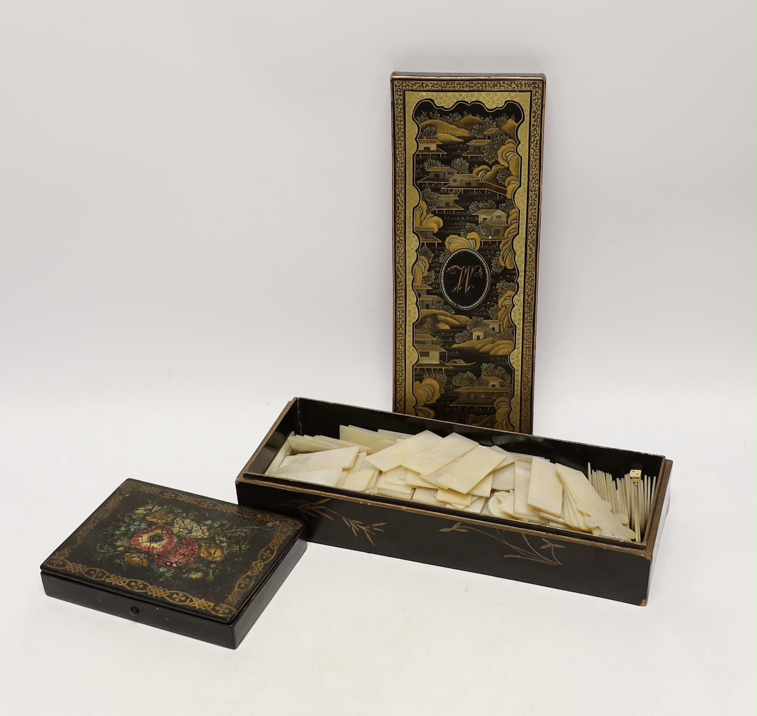 A 19th century Chinese lacquered games box containing a large collection of mother-of-pearl gaming counters and a painted papier mache box, longest 26cm